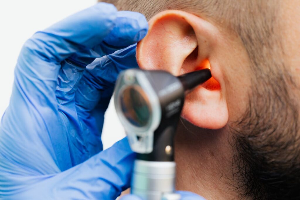 pexels-photo-5206951 Close-up of a doctor using an otoscope to examine a patient's ear in a clinical setting.
